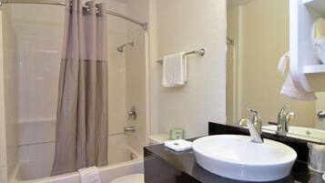 Un baño con bañera, inodoro, lavabo y ducha con puerta de vidrio.