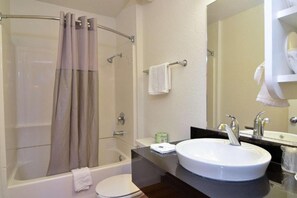 Un baño con bañera, inodoro, lavabo y ducha con puerta de vidrio.