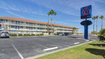 Un motel con estacionamiento, edificios de varios pisos y palmeras.