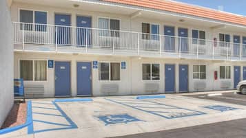 Ein Motel mit mehreren Zimmern, jedes mit einer blauen Tür und dem Rollstuhlgerechter-Symbol.