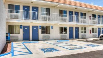 Ein Motel mit mehreren Zimmern, jedes mit einer blauen Tür und einem barrierefreien Eingang.