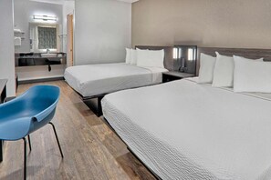 Una habitació d'hotel amb dos llits, una taula de treball, una cadira i un televisor.