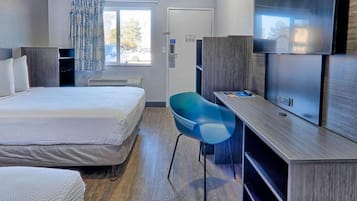 Une chambre d’hôtel avec un lit, un bureau, une chaise, une télévision et une fenêtre.