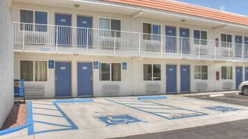 Ein Motel mit mehreren Zimmern, jedes mit einer blauen Tür und dem Rollstuhlgerechter-Symbol.