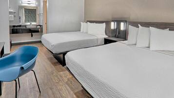 Ein Hotelzimmer mit zwei Betten, einem Schreibtisch, einem Stuhl und einem Fernseher.