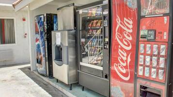 Ein Getränkeautomat mit Coca-Cola-Logo, ein Kühlschrank und ein Gefriertruhe.