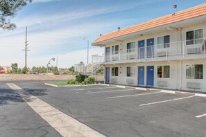 Ein Motel mit Parkplatz, einem eingezäunten Bereich und blauem Himmel.