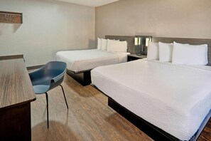 Ein Hotelzimmer mit zwei Betten, einem Schreibtisch, einem Stuhl und einem Nachttisch.