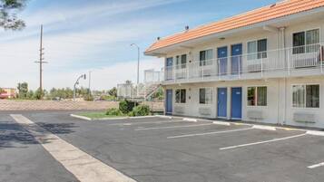 Ein Motel mit Parkplatz, einem eingezäunten Bereich und blauem Himmel.