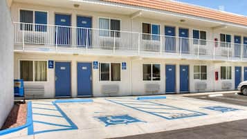 Ein Motel mit mehreren Zimmern, jedes mit einer blauen Tür und einem barrierefreien Eingang.
