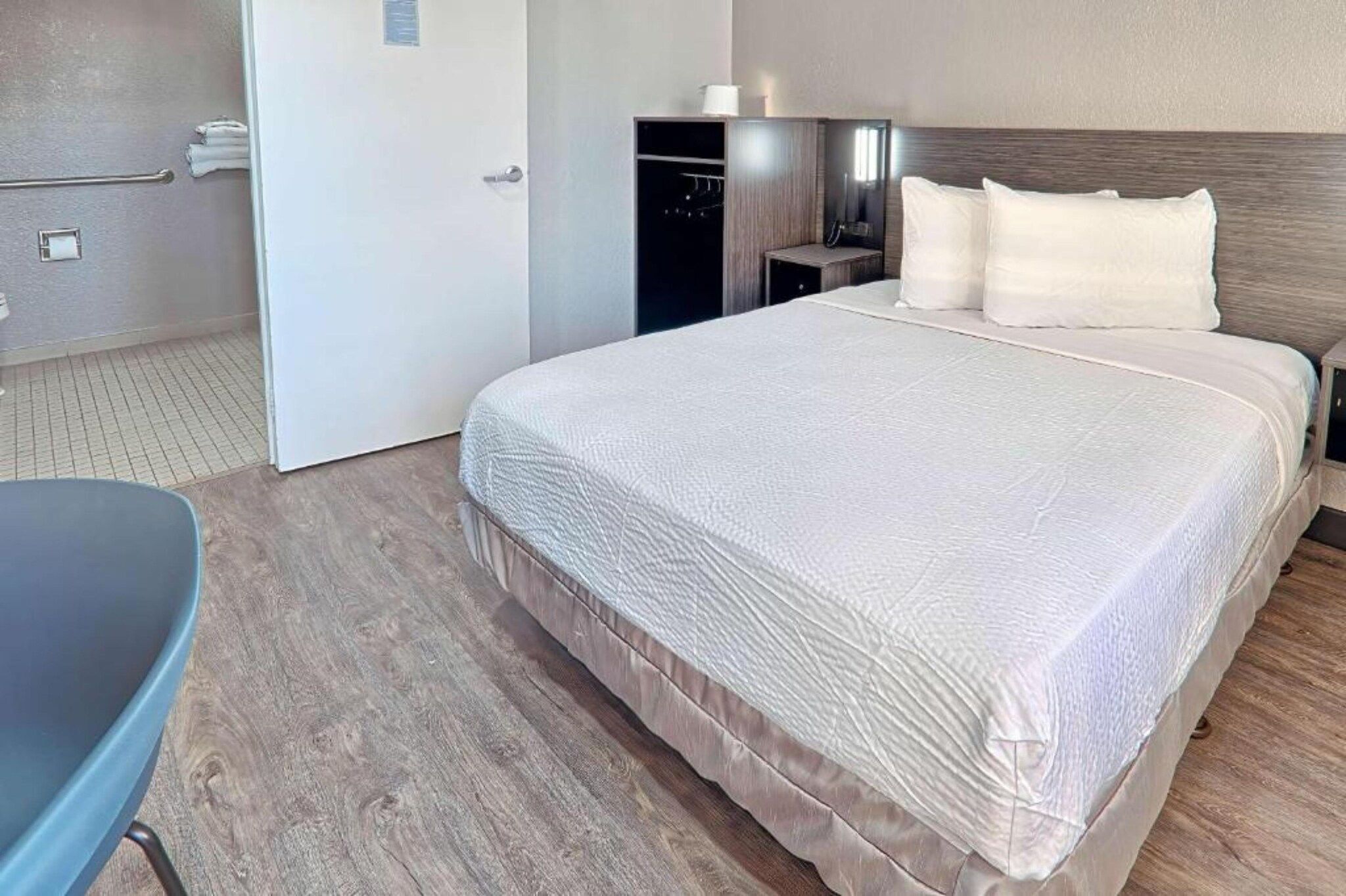 Ein Hotelzimmer mit einem großen Bett, einem Nachttisch, einem Sessel und einem Kleiderschrank.