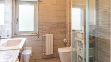 A bathroom with a bathtub, toilet, and a glass shower enclosure.