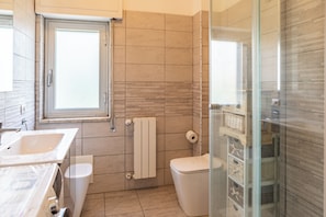 Un baño con bañera, inodoro y cabina de ducha de vidrio.