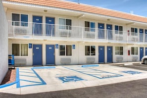 Un motel con varias habitaciones, cada una con una puerta azul y acceso para sillas de ruedas.