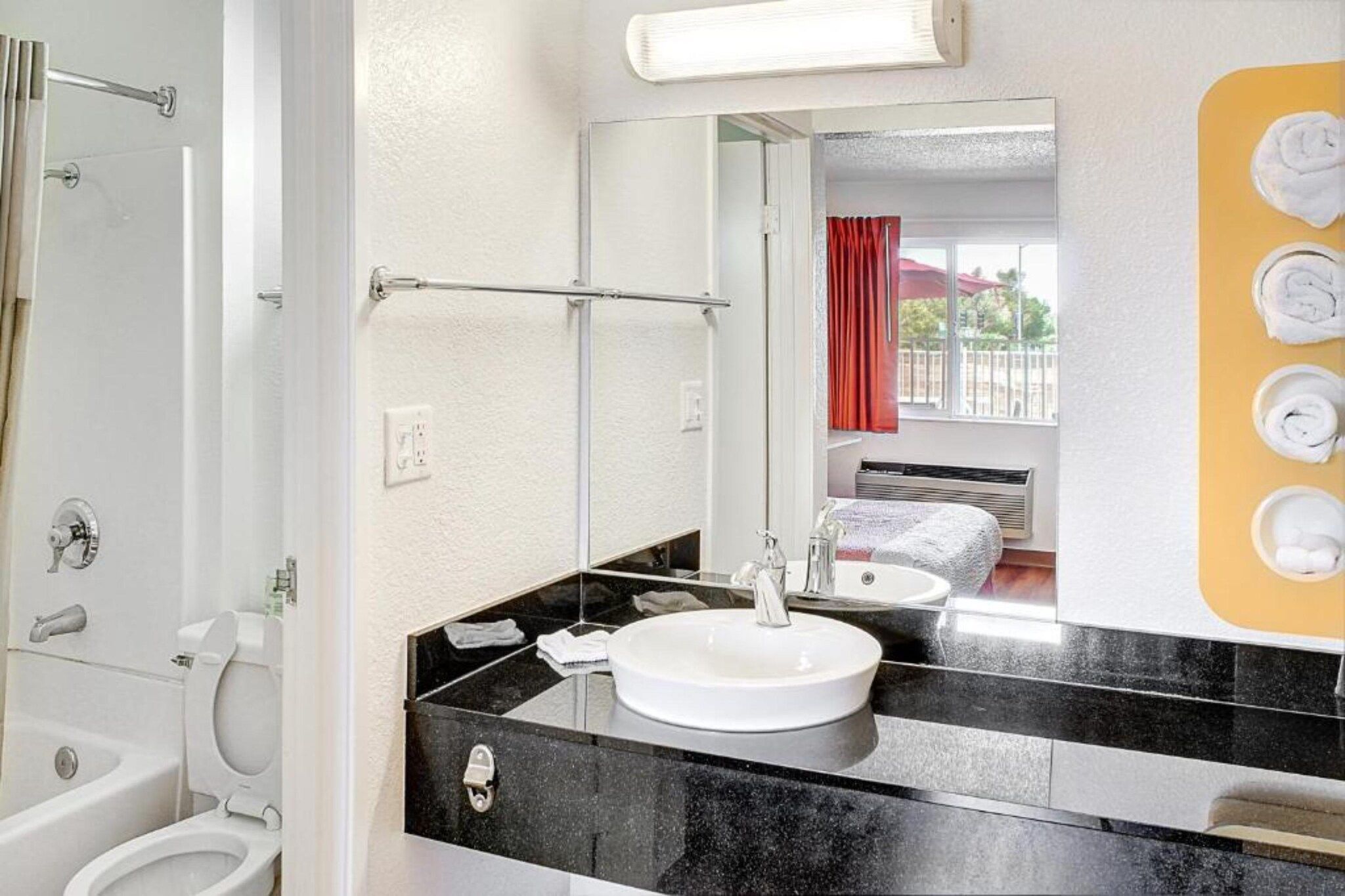 A bathroom with a white sink, black countertop, and a mirror.