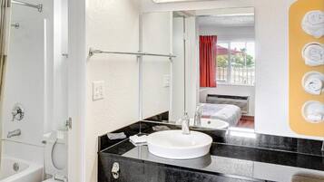 A bathroom with a white sink, black countertop, and a mirror.