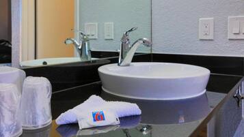 Un baño de hotel con un lavabo redondo, un espejo y una toalla sobre el mostrador.