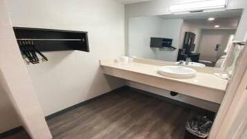 A modern bathroom with a white sink, mirror, and a black towel rack.