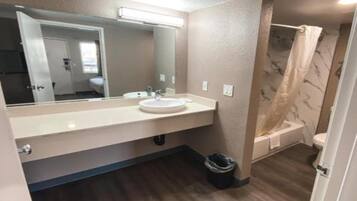 A bathroom with a sink, mirror, and shower.