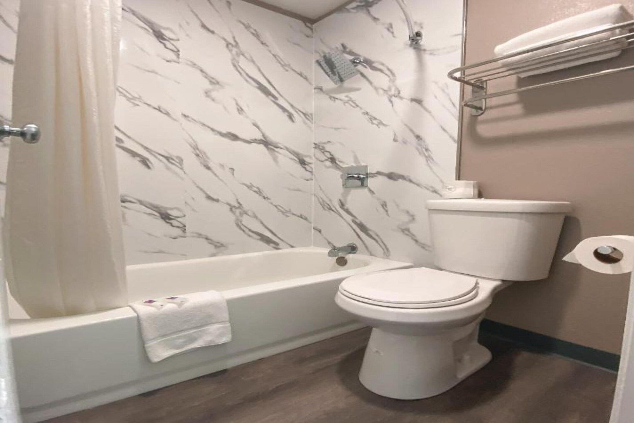 A bathroom with a bathtub, toilet, and marble-patterned walls.