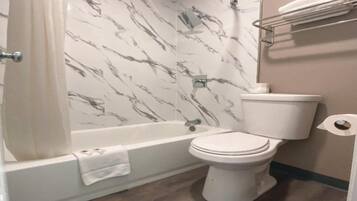 A bathroom with a bathtub, toilet, and marble-patterned walls.