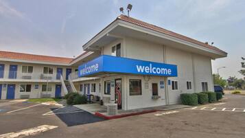 A building with a blue 'welcome' sign, a parking lot, and a clear sky.