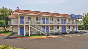 A two-story motel with a red-tiled roof, multiple balconies, and a parking lot.