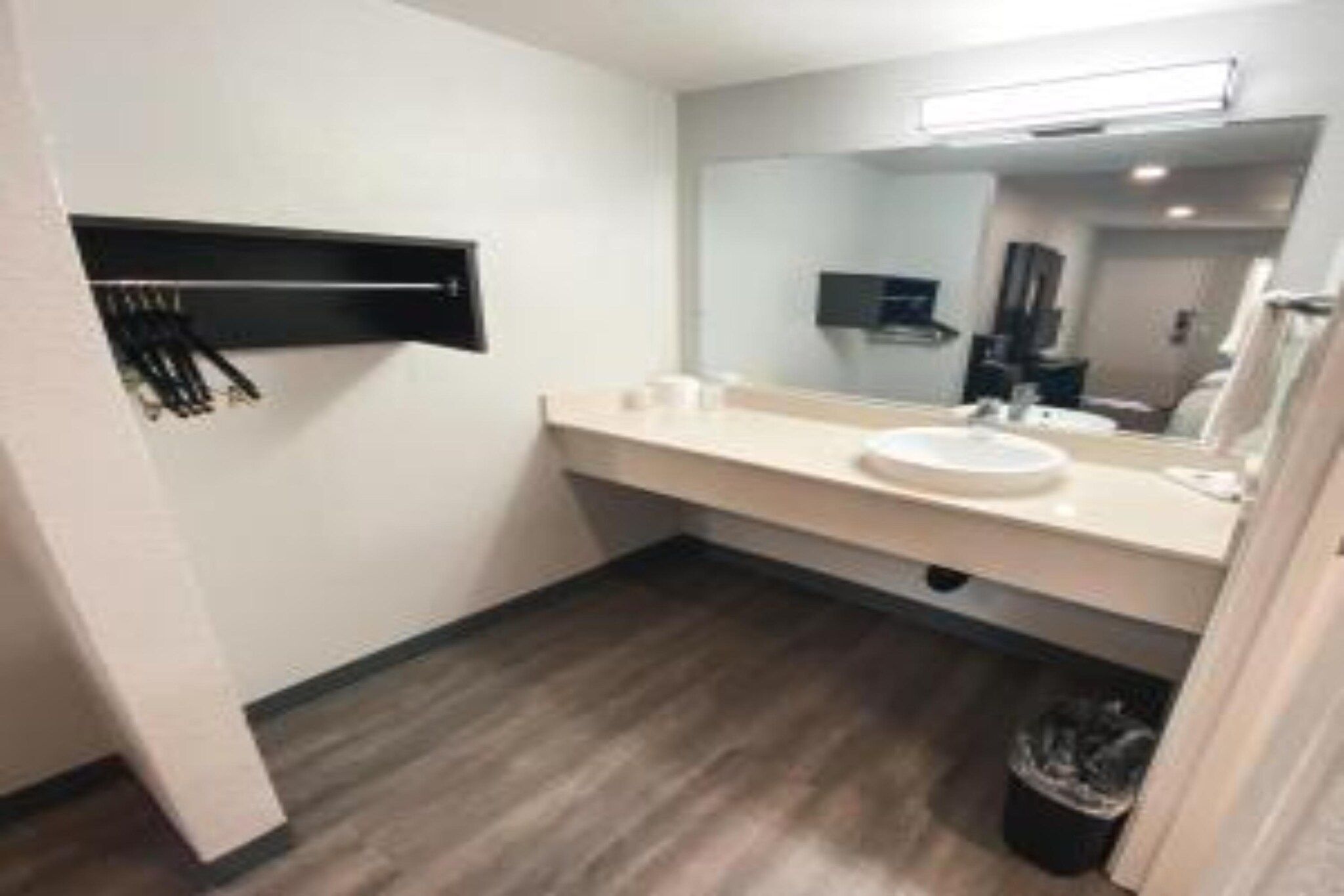 A modern bathroom with a white sink, mirror, and a black towel rack.