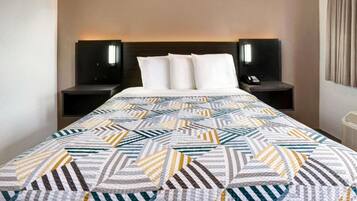 A hotel room with a bed, two bedside tables, and a nightstand with a lamp.