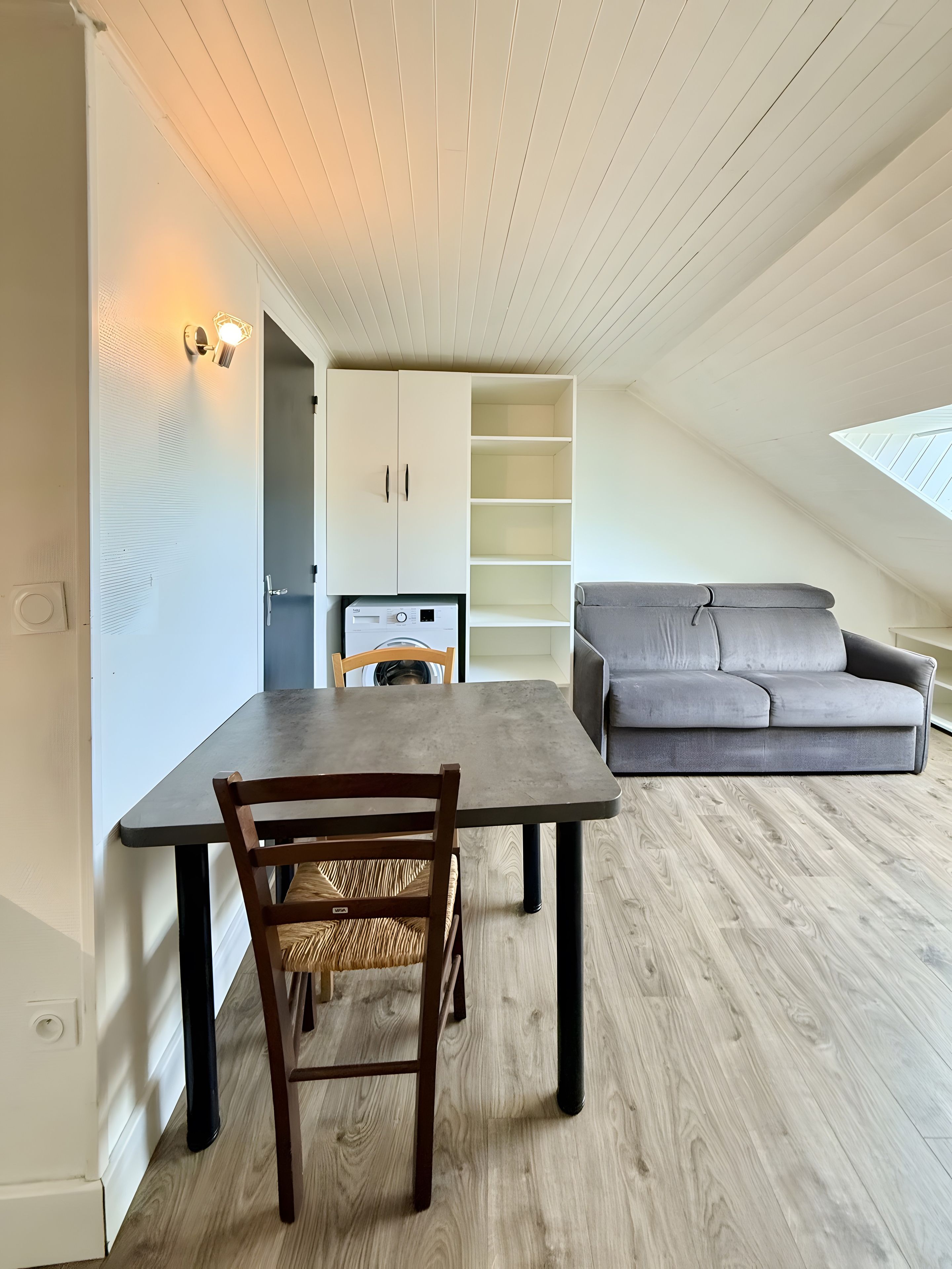 A modern interior with a dining table, a sofa, and a built-in shelving unit.