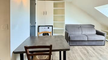 A modern interior with a dining table, a sofa, and a built-in shelving unit.
