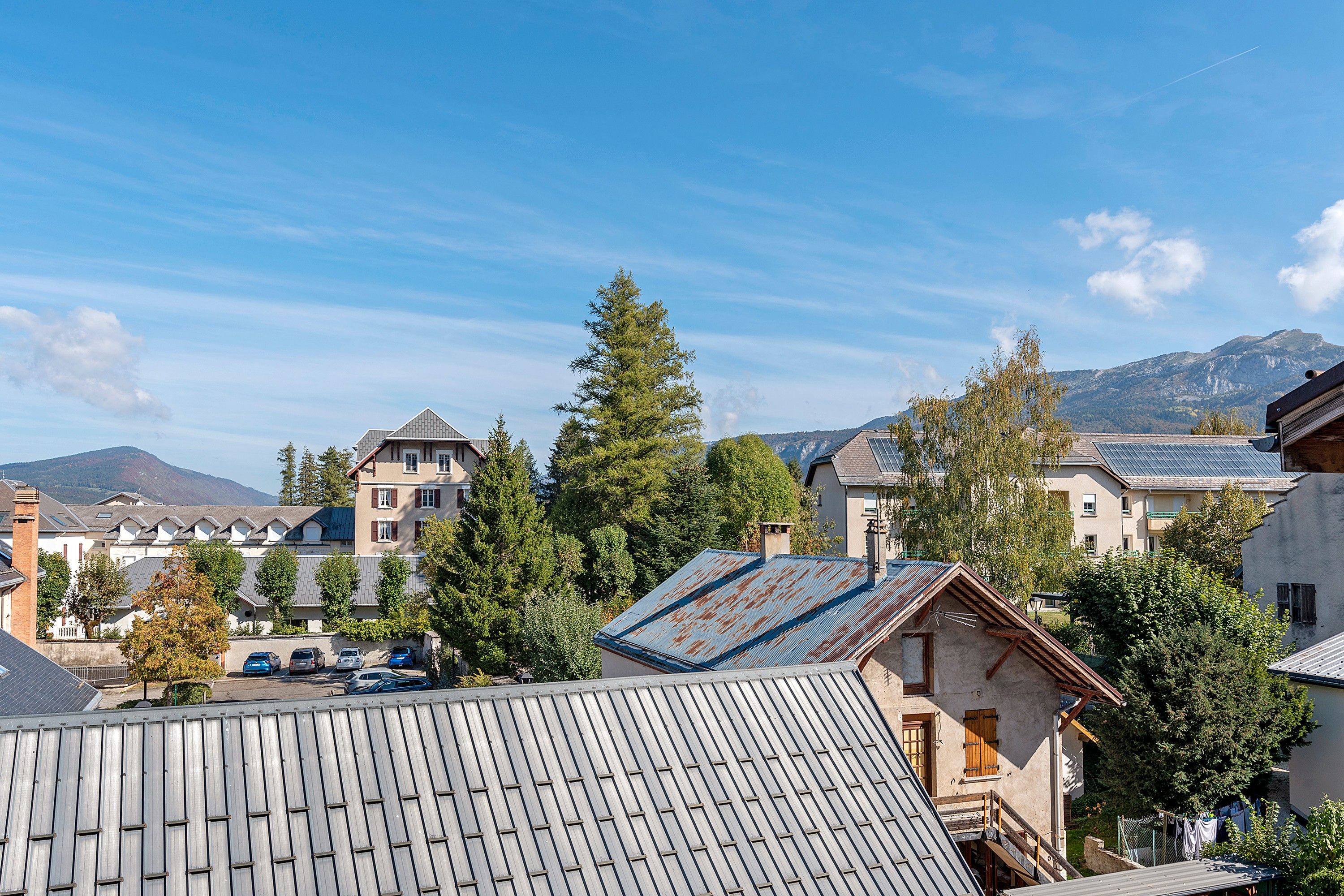 Ett bostadsområde med hus, en parkeringsplats och ett berg i bakgrunden.