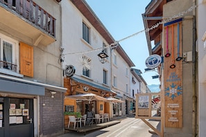 Un carrer estret amb edificis de fusta, zones d'aigüda i indicadors de restaurants.