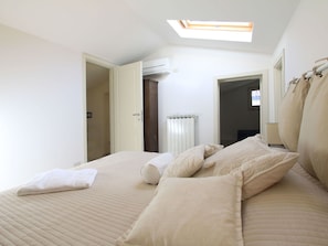Ein Schlafzimmer mit einem Bett, Kissen, einem Heizkörper und einem Oberlicht.