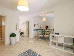 Un interno moderno con un'area pranzo, un tavolo consolle bianco e una pianta in vaso.