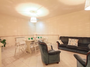 Ein Essbereich mit Tisch, Stühlen, einem Deckenventilator, einer Couch und einem Heizkörper.