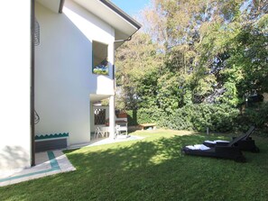 Una proprietà residenziale con patio, area salotto esterna e un giardino rigoglioso.