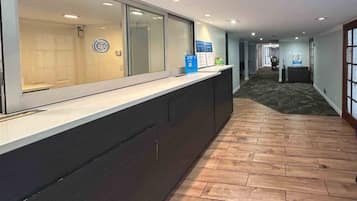 A reception area with a counter, a wooden floor, and a hallway leading to another room.