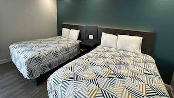 Twin beds with geometric patterned bedding in a room with dark walls and a wooden floor.