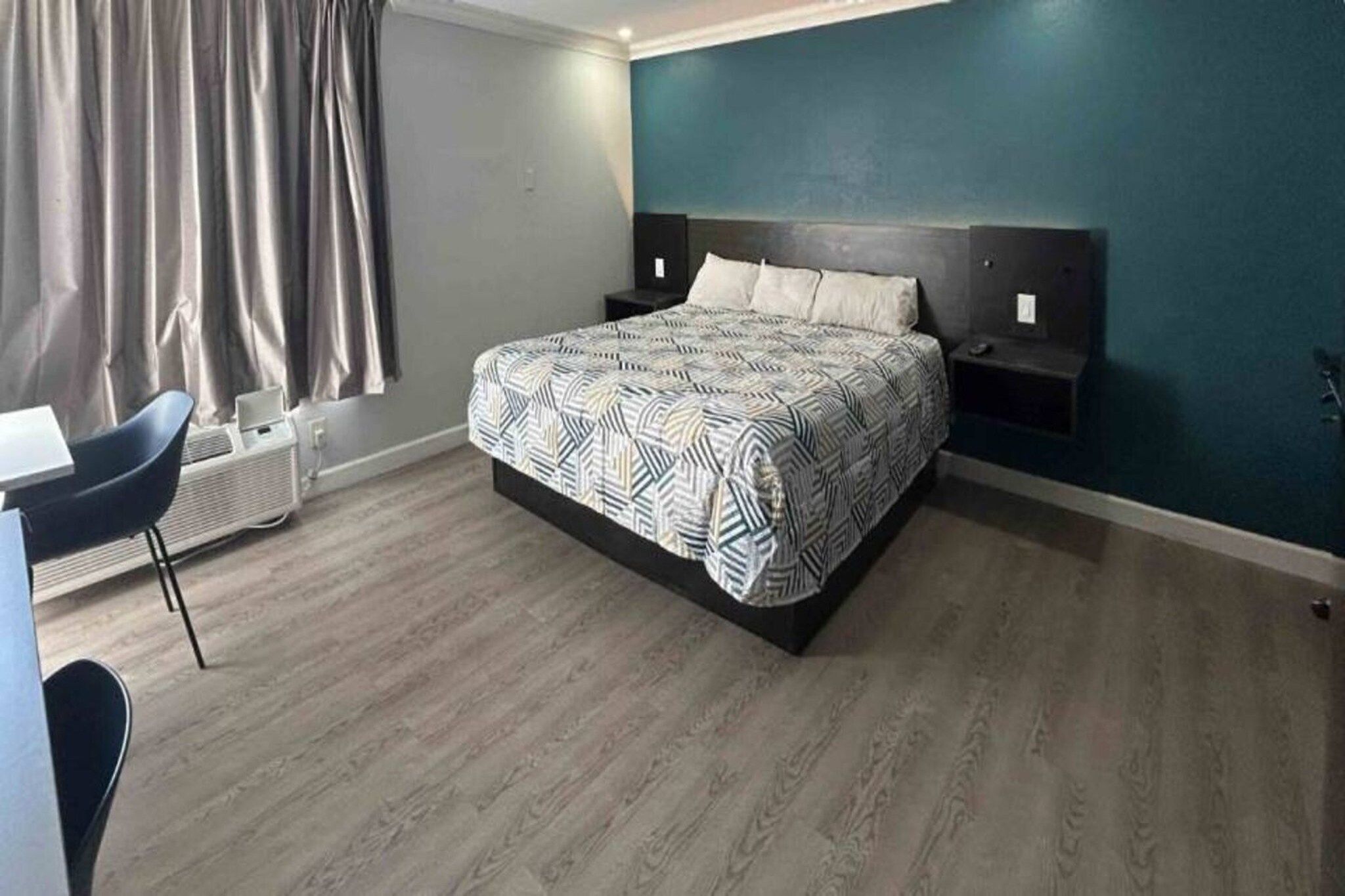 A bedroom with a bed, bedside tables, a desk, and a chair.