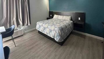 A bedroom with a bed, bedside tables, a desk, and a chair.