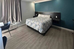 Un dormitorio con cama, mesitas de noche, un escritorio y una silla.