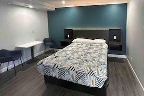 Una habitación de hotel con una cama grande, un escritorio, dos sillas y un televisor.