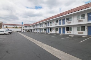 A motel with a parking lot and a single-story building with a red-tiled roof.