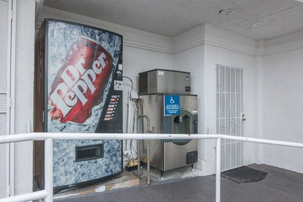 A Dr Pepper vending machine, a handicap-accessible sign, and a door with a security keypad.