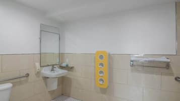 A bathroom with a sink, mirror, toilet, and a towel rack.