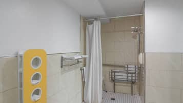 A bathroom with a shower, a hand dryer, and a towel rack.