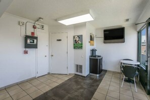Un hall de hotel con una recepción, un cubo de basura, un microondas y un televisor montado en la pared.