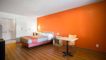 A hotel room with a bed, a desk, and a chair.