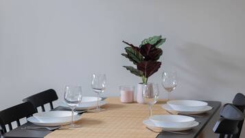 A dining table with chairs, a vase with a plant, and a framed artwork on the wall.